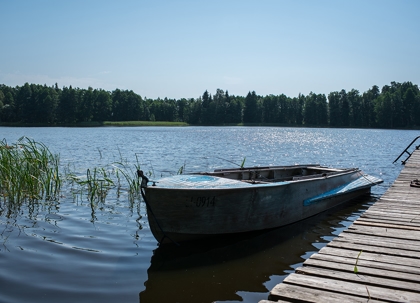 A blue rowboat sits on a wooden dock over calm, rippled water.