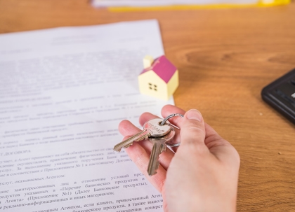 Keys sit atop legal documents with signatures.