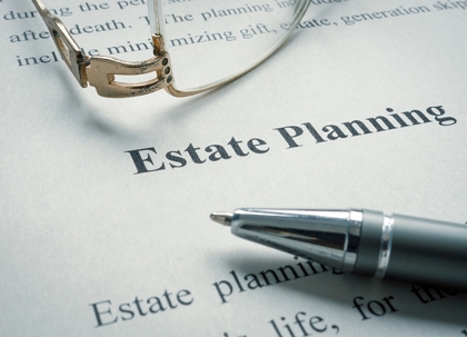 Estate planning documents, glasses, pen, and calculator are on a table.