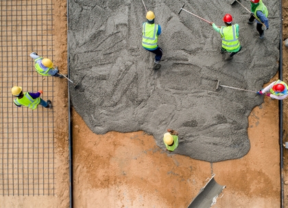 Construction workers are pouring concrete on a building foundation.
