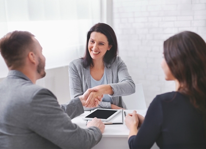 A man and a woman are shaking hands with a third person.