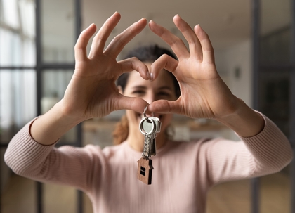 A person is holding house keys shaped like a heart.