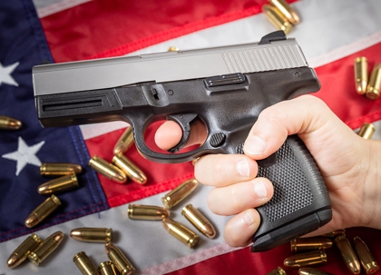 A black handgun, bullets, and the American flag.