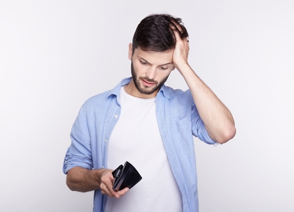 A man holds an empty wallet, looking disappointed.