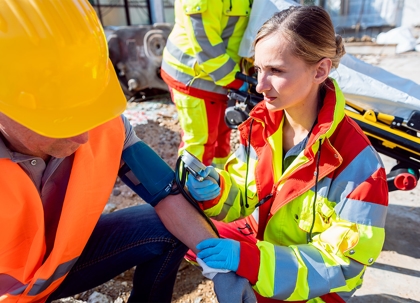 A paramedic is taking a worker's blood pressure on a construction site.