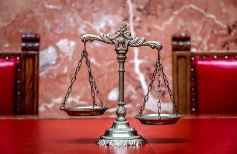 A metallic scale, with ornate details, sits on a red surface.