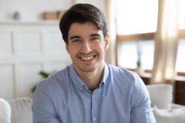 A man with a happy expression, wearing a light blue button-up shirt.